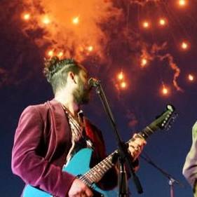 Camilo playing guitar with fireworks in the background